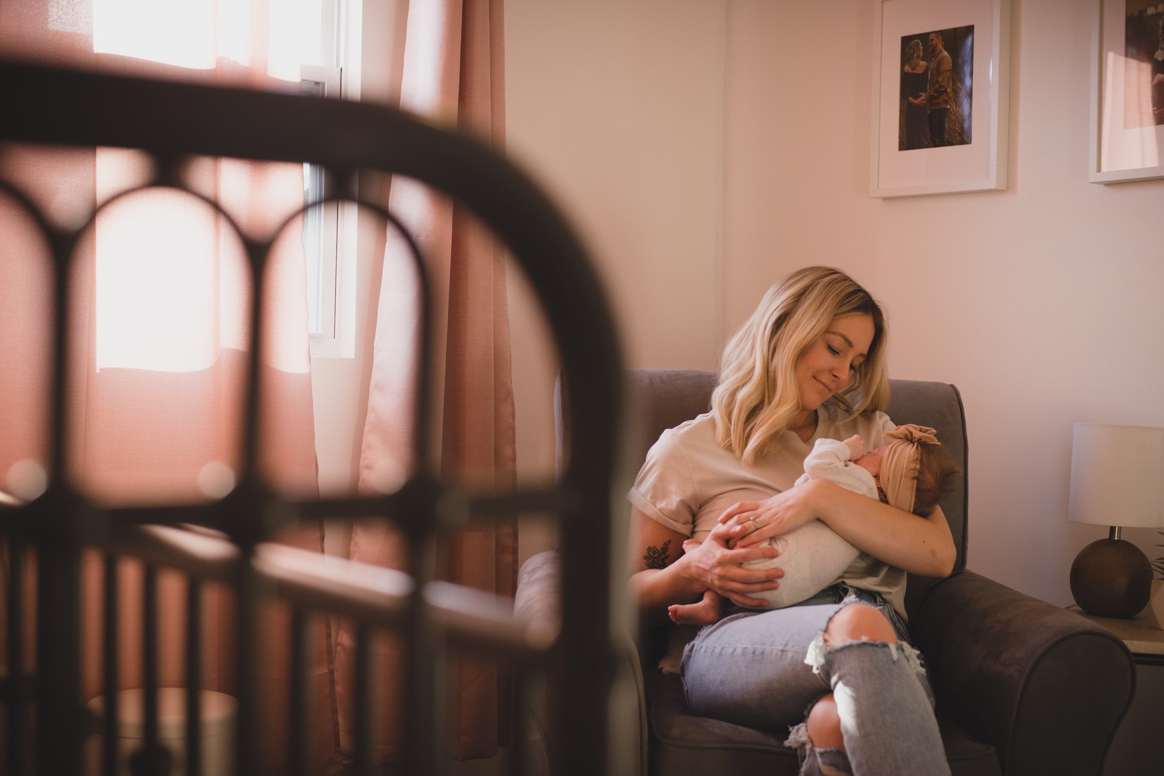 Liz holding her newborn in a nursery filled with soft morning light